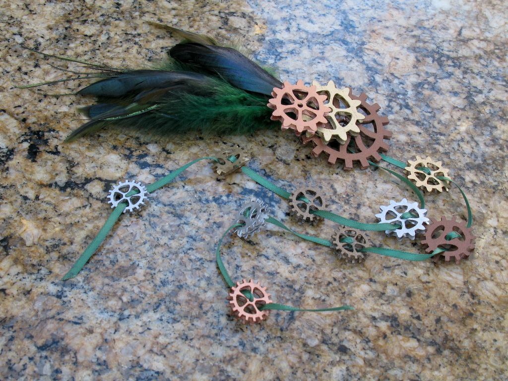 Fascinator made with green feathers, gears, and trailing ribbons strung with mini gears